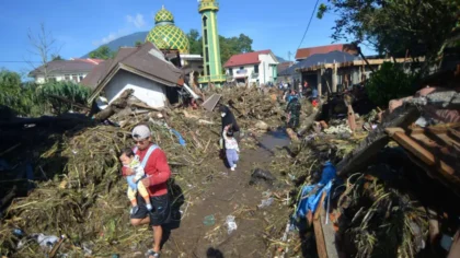 Warga berjalan di atas tumpukan material akibat banjir bandang di Jorong Galuang, Nagari Sungai Pua, Agam, Sumatera Barat, Senin (13/05). ANTARA FOTO/Iggoy el Fitra